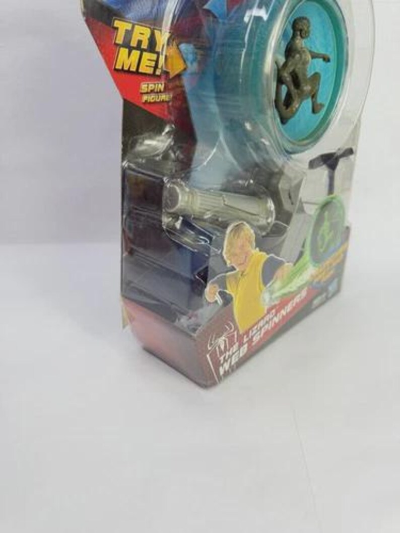 May include: A Spider-Man toy featuring a spinning figure in a clear plastic package. The package has the text "TRY ME!" and "SPIN FIGURE". The toy includes a small figure and a web spinner.