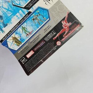 Puede incluir: Un paquete de figuras de acci&oacute;n de Spider-Man 3 parcialmente visible. El paquete presenta im&aacute;genes de Spider-Man y otros personajes, con texto que incluye "COLLECT all the SPIDER-MAN 3 action figures!" y "MARVEL". El paquete tiene un dise&ntilde;o azul y blanco.