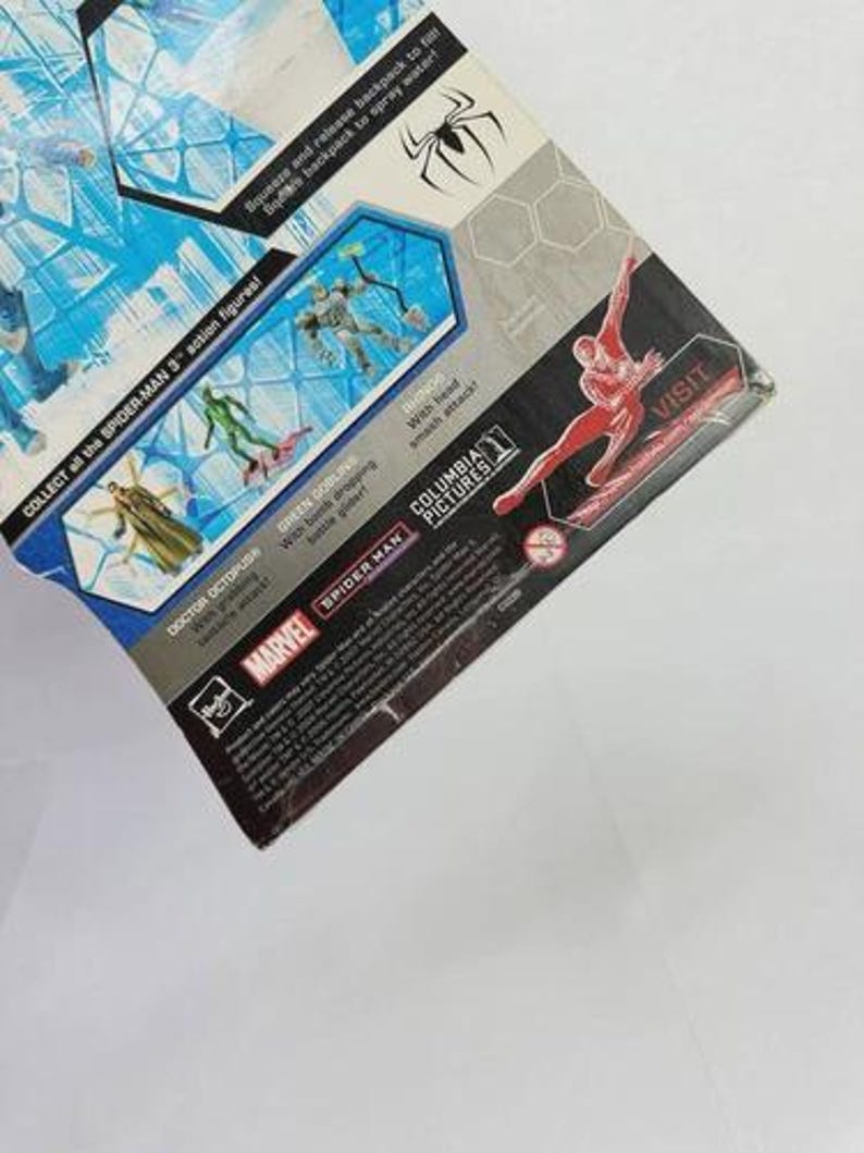 Puede incluir: Un paquete de figuras de acci&oacute;n de Spider-Man 3 parcialmente visible. El paquete presenta im&aacute;genes de Spider-Man y otros personajes, con texto que incluye "COLLECT all the SPIDER-MAN 3 action figures!" y "MARVEL". El paquete tiene un dise&ntilde;o azul y blanco.