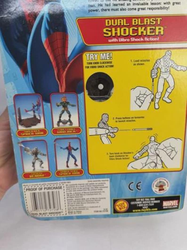 May include: A blue and red Spider-Man action figure package. The packaging features the words "DUAL BLAST SHOCKER" and "TRY ME!". The package also includes illustrations of Spider-Man and other characters.