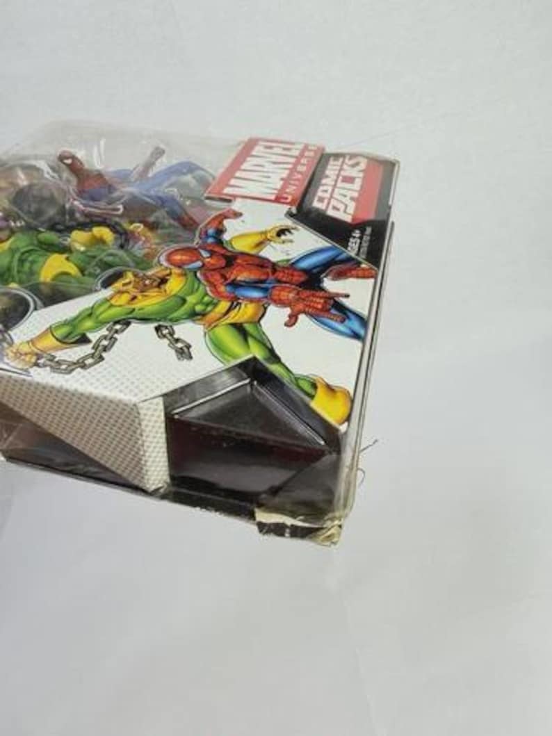 K&ouml;nnte beinhalten: Marvel Universe Comic Packs mit Actionfiguren von Spider-Man, Vision und anderen Charakteren. Die Verpackung enth&auml;lt das Marvel-Logo und die Worte "Comic Packs". Die Figuren befinden sich in einer transparenten Kunststoffverpackung.