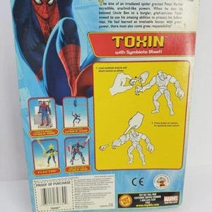 Puede incluir: La parte trasera de un paquete de figuras de acci&oacute;n de Spider-Man. El paquete presenta una gran ilustraci&oacute;n de Spider-Man y el texto "TOXIN with Symbiote Blast!" junto con otros personajes de Spider-Man.