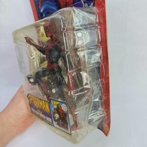 Peut inclure: Figurine de Spider-Man dans un emballage plastique. La figurine est rouge et noire, avec un costume d&eacute;taill&eacute;. L'emballage a un fond rouge et bleu avec le logo Spider-Man et des illustrations du personnage. La figurine mesure environ 15 cm de haut.