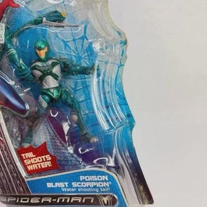 Puede incluir: Figura de acci&oacute;n Poison Blast Scorpion de la serie Spider-Man, en un bl&iacute;ster transparente. La figura es verde y plateada, con una cola que dispara agua. El embalaje incluye el texto "Tail Shoots Water!"