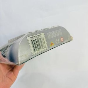 May include: A packaged action figure, partially visible, with a barcode and the text "68061 NEW GOBLIN PROOF OF PURCHASE". The packaging is silver and clear plastic. The figure is held by a hand.