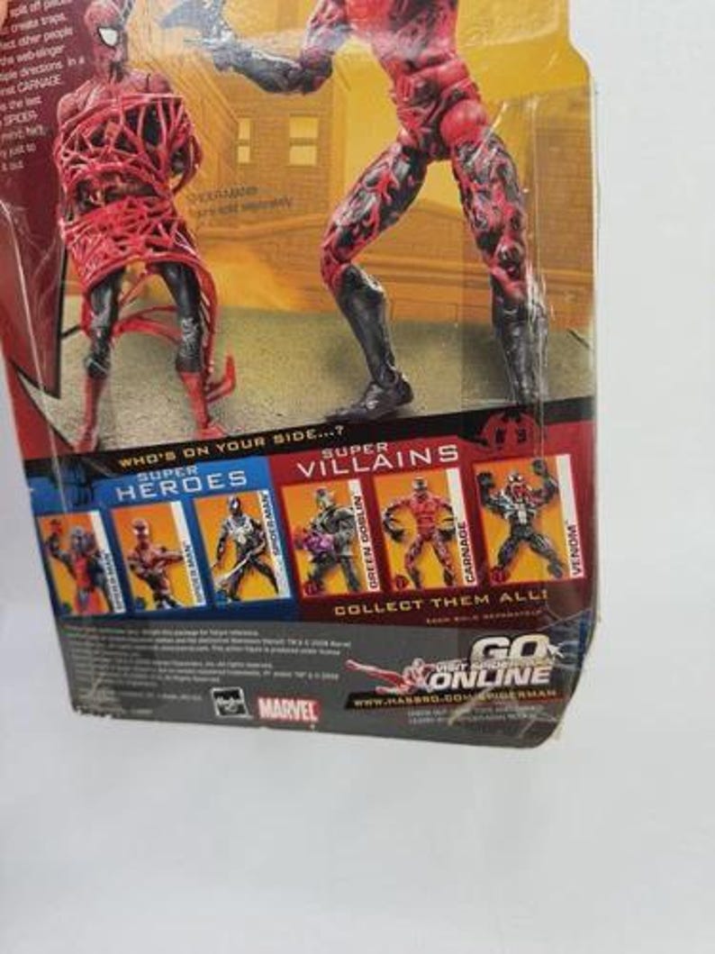 May include: Action figure packaging featuring two Carnage figures. The packaging includes images of other Marvel characters, including Spider-Man, Green Goblin, and Venom. The text "Who's on your side...?" is visible.