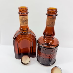 Puede incluir: Dos botellas de vidrio color &aacute;mbar con tapones de corcho y tapas met&aacute;licas. Una botella es cuadrada, la otra redonda con un dise&ntilde;o floral en relieve. Las botellas tienen etiquetas que dicen "Stetson". Las tapas est&aacute;n a un lado.