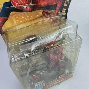 May include: Spider-Man action figure in a clear plastic package. The figure is red and blue, with a detailed costume. The packaging features a cityscape background and the Spider-Man logo. Ages 4 and up.