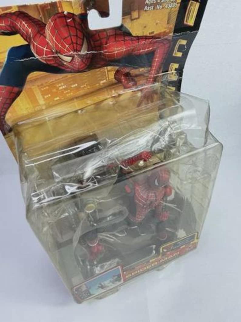 May include: Spider-Man action figure in a clear plastic package. The figure is red and blue, with a detailed costume. The packaging features a cityscape background and the Spider-Man logo. Ages 4 and up.