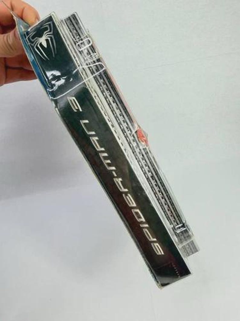 Peut inclure: Emballage scell&eacute; d'une figurine Spider-Man 3. L'emballage est noir avec des lettres argent&eacute;es et un logo d'araign&eacute;e blanc. La figurine est visible &agrave; travers le plastique transparent.