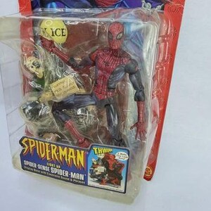 Peut inclure: Figurine articul&eacute;e de Spider-Man dans un emballage plastique. La figurine est rouge et noire, avec un motif de toile d'araign&eacute;e d&eacute;taill&eacute;. L'emballage comprend le logo Spider-Man et le texte "Spider-Sense Spider-Man".