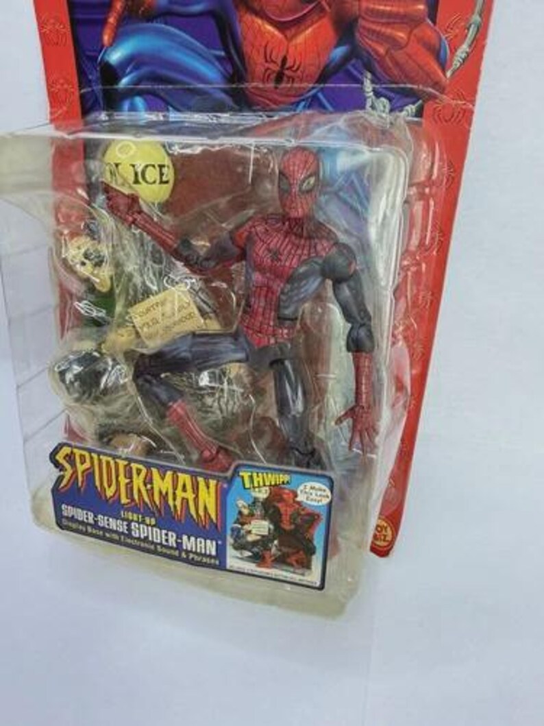Peut inclure: Figurine articul&eacute;e de Spider-Man dans un emballage plastique. La figurine est rouge et noire, avec un motif de toile d'araign&eacute;e d&eacute;taill&eacute;. L'emballage comprend le logo Spider-Man et le texte "Spider-Sense Spider-Man".