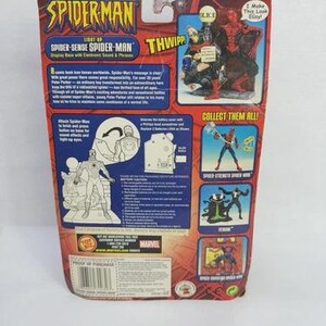 Peut inclure: Emballage vintage de figurine Spider-Man. L'emballage est principalement rouge et bleu, avec le logo Spider-Man et des illustrations de personnages. Le texte comprend "Spider-Sense Spider-Man" et "Collect Them All!"