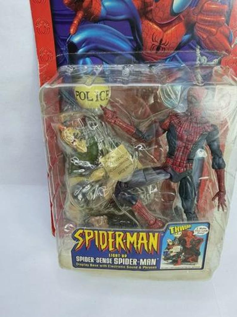 Peut inclure: Figurine articul&eacute;e de Spider-Man dans un emballage plastique transparent. La figurine est rouge et noire, avec un costume d&eacute;taill&eacute;. L'emballage porte l'inscription "SPIDER-MAN" et "SPIDER-SENSE SPIDER-MAN".