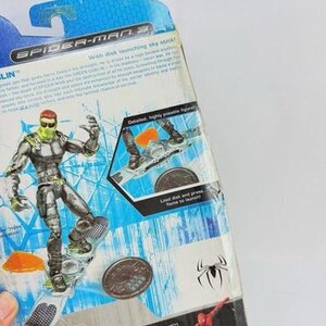 May include: A Spider-Man 3 action figure of the Green Goblin on a sky stick, with a green and silver color scheme. The packaging includes the Marvel and Spider-Man logos, and the text "With disk launching sky stick!"