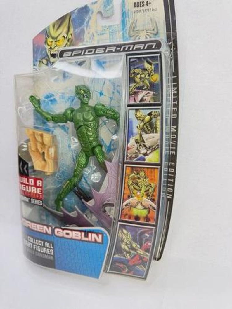 May include: A Green Goblin action figure from the Spider-Man movie series, packaged in a clear plastic case. The figure is green with a detailed costume. The packaging includes the text "GREEN GOBLIN" and "COLLECT ALL FIGHT FIGURES".