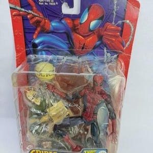 Peut inclure: Figurine de Spider-Man dans un emballage plastique. La figurine est rouge et bleue, avec un costume d&eacute;taill&eacute;. L'emballage pr&eacute;sente le logo Spider-Man et le texte "Spider-Sense Spider-Man". L'emballage est marqu&eacute; "Ages 4 and Up".
