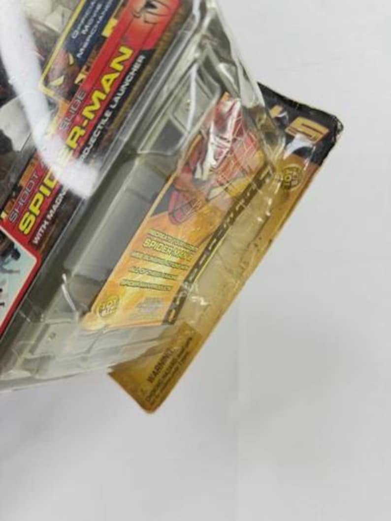 May include: Sealed Spider-Man toy package. The packaging features the words "SLIDE SPIDER-MAN PROJECTILE LAUNCHER" and "SHOOT SPIDER WITH MAGN". The package has a red, yellow, and black color scheme, with images of Spider-Man.