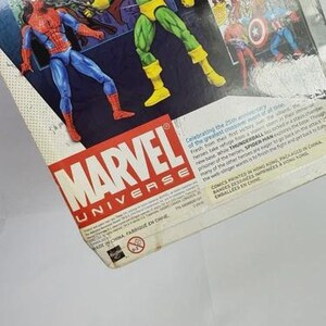 K&ouml;nnte beinhalten: Marvel Universe Actionfigurenverpackung mit Spider-Man und Thunderball. Die Verpackung enth&auml;lt Comic-Kunst und Text. Das Marvel-Logo ist prominent in Rot und Wei&szlig; dargestellt.