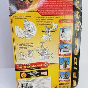 May include: The back of a Spider-Man action figure package. The package is yellow and black, with instructions and images of the action figure. The text on the package includes "Spin & Kick Spider-Man" and "Collect Them All!"