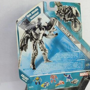 Puede incluir: Figura de acci&oacute;n de Spider-Man en su embalaje. La figura es plateada y negra con lanzador de misiles web. El embalaje presenta una motocicleta y otros personajes de Marvel. El texto "COLLECT them all" es visible.