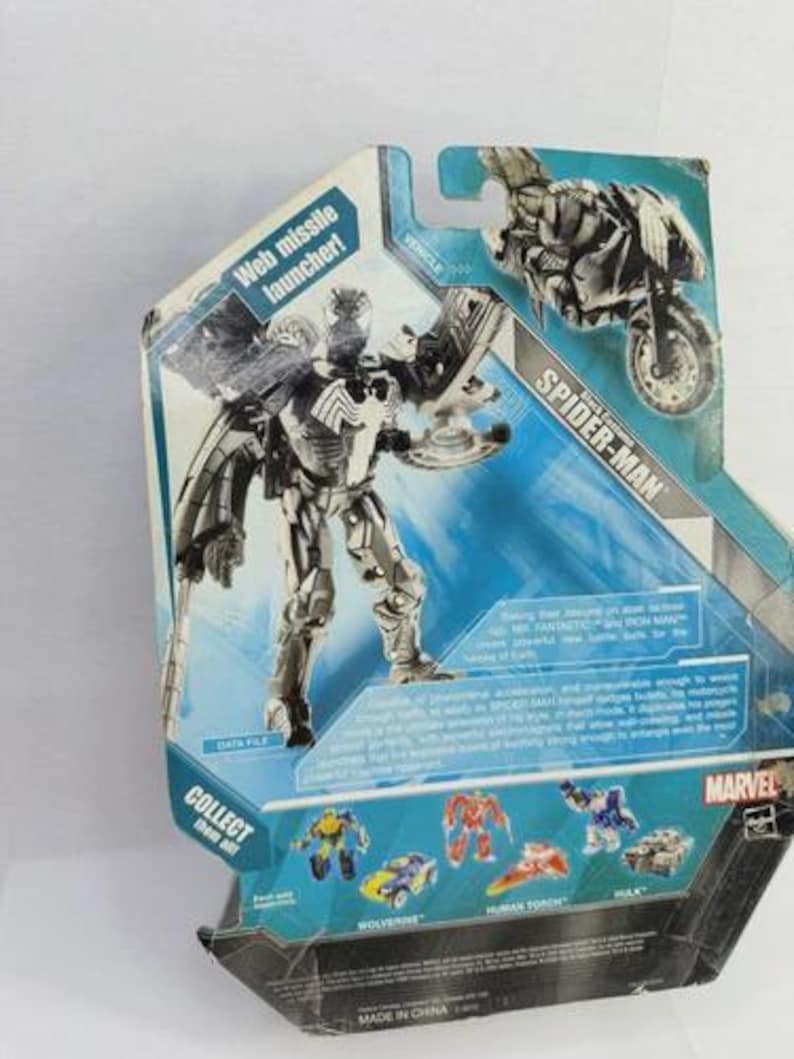 Puede incluir: Figura de acci&oacute;n de Spider-Man en su embalaje. La figura es plateada y negra con lanzador de misiles web. El embalaje presenta una motocicleta y otros personajes de Marvel. El texto "COLLECT them all" es visible.