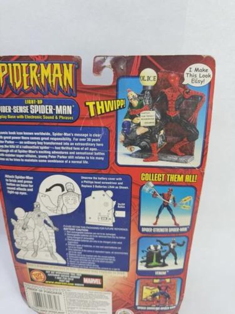 Peut inclure: Emballage de figurine Spider-Man avec le texte "Spider-Man" et "Light-Up Spider-Sense Spider-Man". L'emballage rouge et bleu pr&eacute;sente des images de Spider-Man et d'autres personnages.