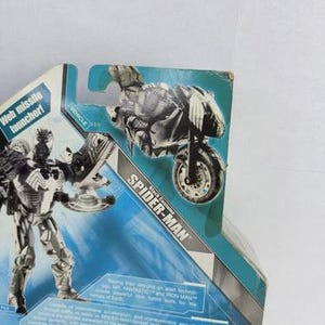 Puede incluir: Figura de acci&oacute;n de Spider-Man en blanco y negro, con una moto. El embalaje incluye el texto "Web missile launcher!" y "Spider-Man". Producto Marvel.