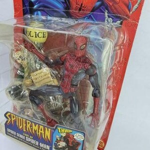 Peut inclure: Figurine articul&eacute;e de Spider-Man dans un emballage plastique. La figurine est rouge et noire, avec un costume d&eacute;taill&eacute;. L'emballage pr&eacute;sente le logo Spider-Man et le texte "Spider-Sense Spider-Man". L'arri&egrave;re-plan montre une illustration de Spider-Man.
