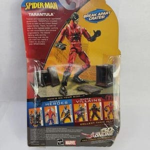May include: A Spider-Man action figure of the character Tarantula, packaged on a cardboard backing. The figure is red and black, with the words "Spider-Man" and "Tarantula" printed on the packaging. The packaging also includes the text "Break Apart Crates!"
