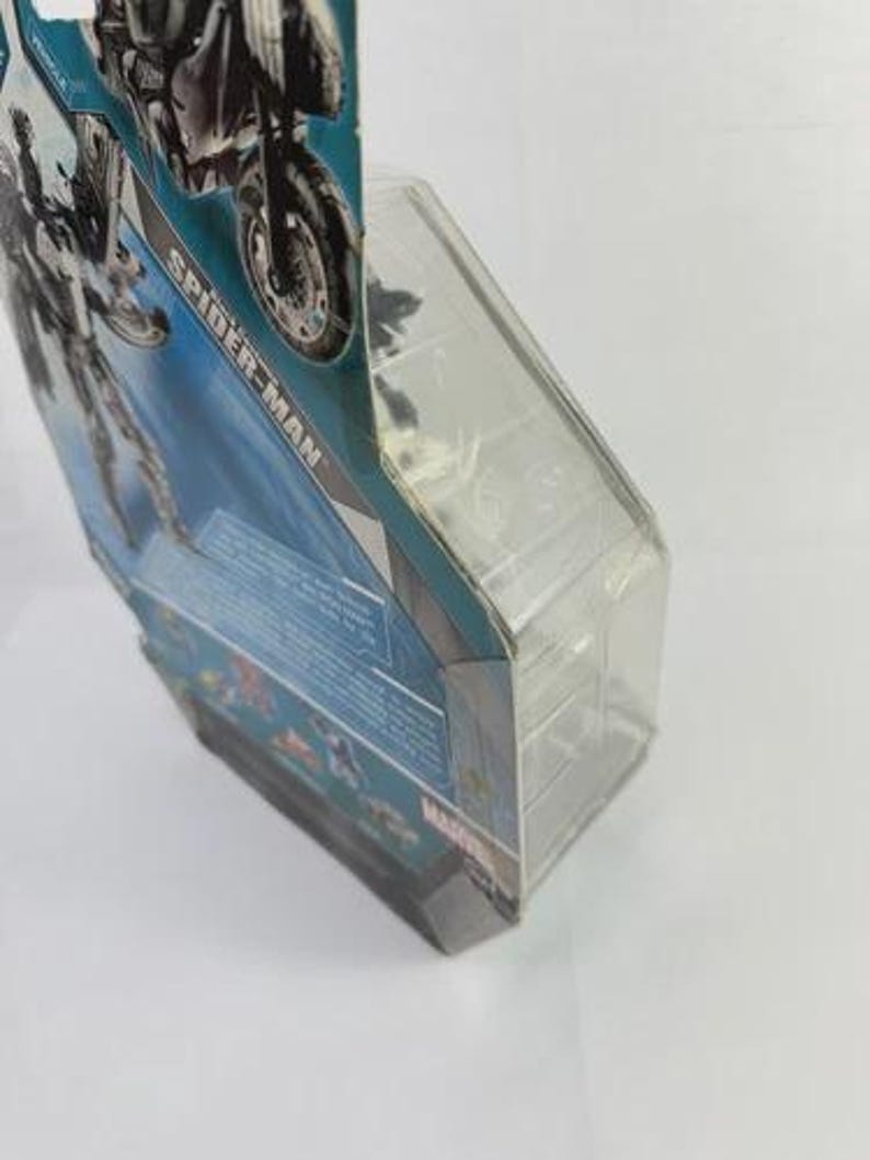 Puede incluir: Una figura de acci&oacute;n de Spider-Man en un paquete de pl&aacute;stico transparente. El embalaje tiene un dise&ntilde;o azul y blanco con las palabras "Spider-Man" impresas. La figura es parcialmente visible.