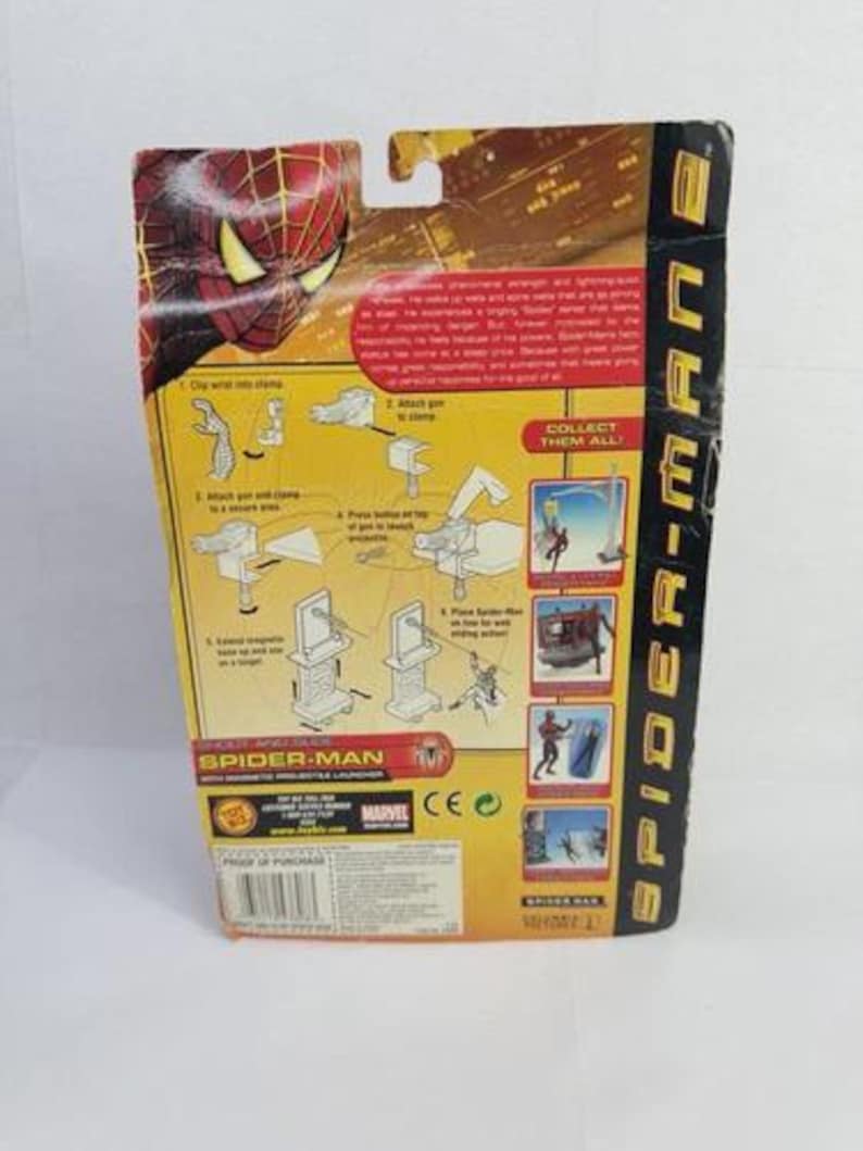 May include: Back of a Spider-Man 2 action figure package. The packaging is yellow, red, and black, with illustrations and text. The Spider-Man logo and character image are visible. The package includes instructions and the phrase "Collect Them All!"