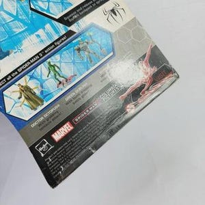 Puede incluir: Un paquete parcialmente visible para figuras de acci&oacute;n de Spider-Man 3. El embalaje presenta im&aacute;genes de Doctor Octopus y Green Goblin. Los logotipos de Marvel y Spider-Man son visibles. El paquete tiene un dise&ntilde;o azul y blanco con el texto "Squeeze and release backpack to spray water!"