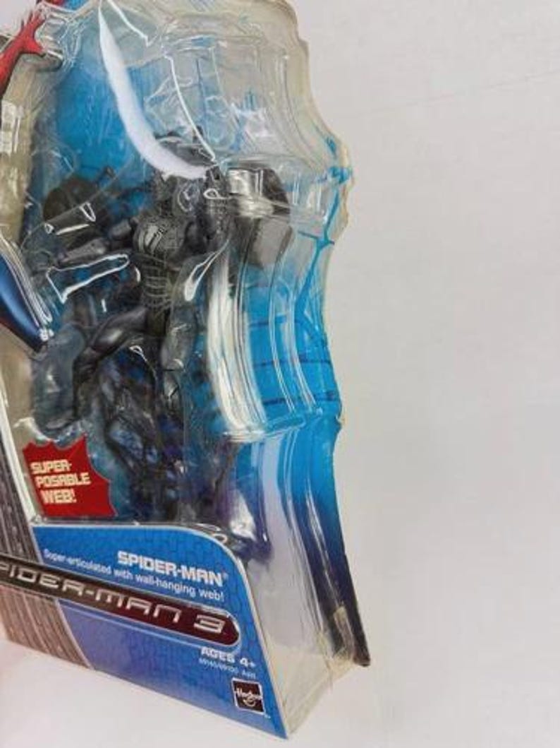 Peut inclure: Figurine Spider-Man dans un emballage plastique transparent. La figurine est noire et bleue, avec un motif de toile d'araign&eacute;e. L'emballage a des accents bleus et le texte "SPIDER-MAN 3". Il est indiqu&eacute; "Super articul&eacute; avec toile d'araign&eacute;e!"