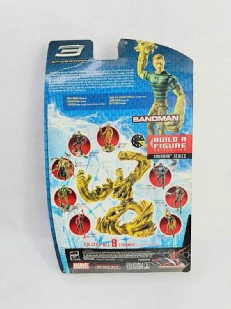 May include: The rear of a Spider-Man 3 Sandman action figure package. The blue packaging displays images of the Sandman character and other figures from the "Build a Figure" collection. The text "Sandman Series" is visible.