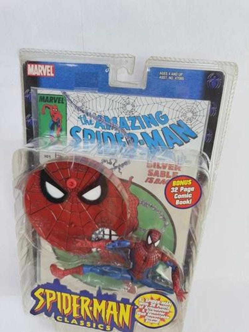 May include: A Spider-Man action figure from the Spider-Man Classics series, packaged in a clear plastic blister pack. The figure is red and blue, with a red spider-web-themed base. The packaging includes the Marvel logo and the text "The Amazing Spider-Man."