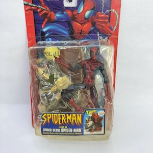 Peut inclure: Figurine de Spider-Man dans un emballage plastique. La figurine est rouge et noire, avec une base d'exposition comprenant des sons et des phrases &eacute;lectroniques. L'emballage pr&eacute;sente le logo Spider-Man et le texte "Light-Up Spider-Sense Spider-Man".