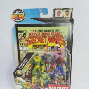 K&ouml;nnte beinhalten: Marvel Secret Wars Comic-Pack mit Spider-Man und Thunderball Actionfiguren. Die Verpackung zeigt Comic-Cover-Art mit dem Text "The Crisis Within!" und "Marvel Universe Comic Packs". Die Verpackung ist mit "Ages 4+" gekennzeichnet.