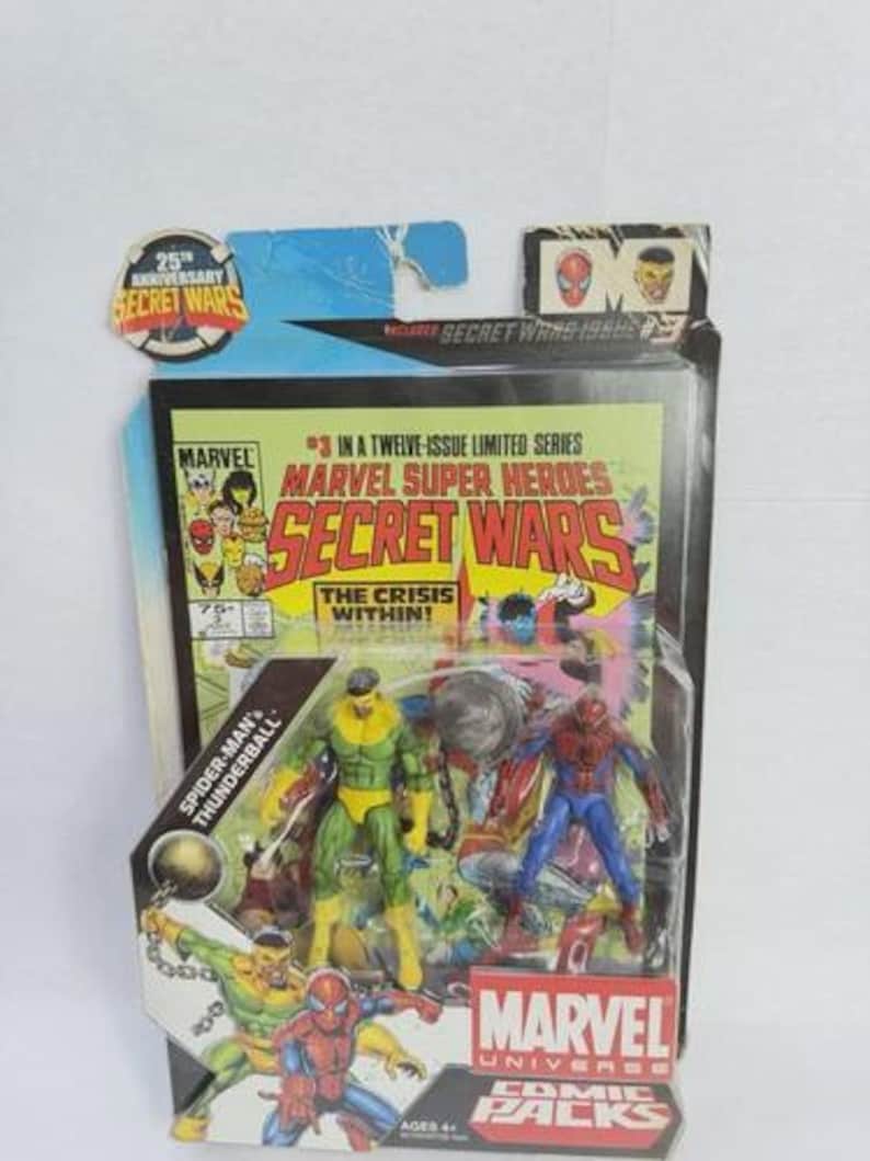 K&ouml;nnte beinhalten: Marvel Secret Wars Comic-Pack mit Spider-Man und Thunderball Actionfiguren. Die Verpackung zeigt Comic-Cover-Art mit dem Text "The Crisis Within!" und "Marvel Universe Comic Packs". Die Verpackung ist mit "Ages 4+" gekennzeichnet.