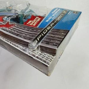 Puede incluir: Paquete sellado de figura de acci&oacute;n de Spider-Man. La caja es azul y presenta las palabras "Spider-Man" y "Poison Blast Scorpion". El paquete est&aacute; envuelto en pl&aacute;stico transparente.