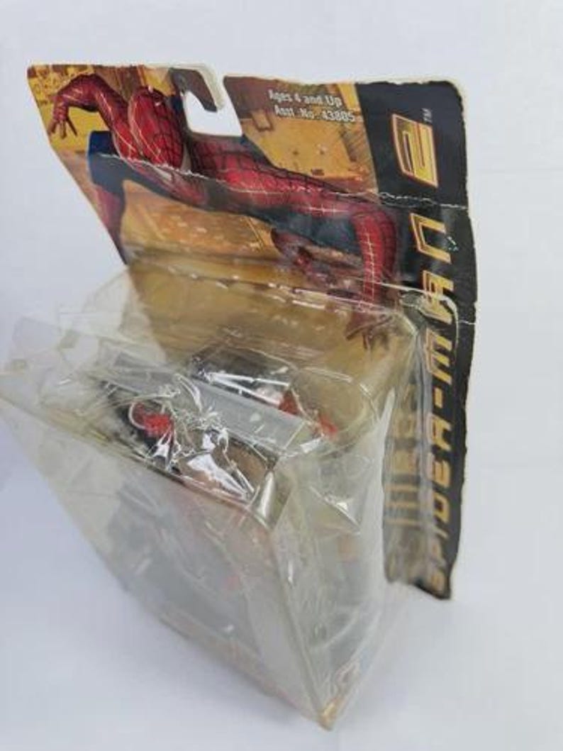 May include: Sealed Spider-Man action figure in original packaging. The figure is red and blue, with a black web design. The packaging is a cardboard backing with a clear plastic front, featuring the Spider-Man logo and character art.