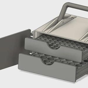Puede incluir: Un estuche de almacenamiento rectangular de color gris claro con un asa superior y dos cajones extraíbles. Los cajones tienen frentes de color gris oscuro con aberturas circulares y bandejas internas con múltiples compartimentos.