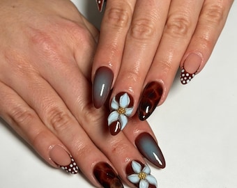 Unhas postiças personalizadas em degradê marrom e azul, com flores 3D e bolinhas, conjunto de unhas reutilizáveis em tons terrosos.