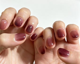 Unhas postiças personalizadas em degradê translúcido vermelho vinho, curtas e redondas, com acabamento brilhante e minimalista para um estilo delicado no dia a dia.