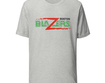 Könnte beinhalten: Hellgraues T-Shirt mit dem Text "BOSTON BLAZERS" in Grün und Rot. Das Wort "BLAZERS" ist in einer fetten, kantigen Schriftart mit einem roten "Z" in der Mitte. Das Wort "BOSTON" steht über dem Wort "BLAZERS".