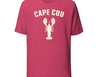 Könnte beinhalten: Rotes T-Shirt mit kurzen Ärmeln und dem Text "CAPE COD" in verblichenem Weiß, über einer weißen Hummer-Grafik. Das Shirt hat einen Rundhalsausschnitt und einen Vintage-Look.