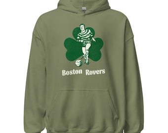 Könnte beinhalten: Olivgrüner Kapuzenpullover mit einem grünen Kleeblatt, einer Grafik eines Fußballspielers und dem weißen Text "Boston Rovers". Er hat eine Vordertasche und eine Kapuze mit Kordelzug.