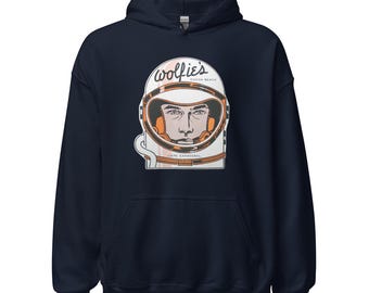 Könnte beinhalten: Marineblauer Kapuzenpullover mit einer Grafik eines Astronautenhelms. Der Helm trägt den Text "wolfie's COCOA BEACH CAPE CANAVERAL". Der Helm ist weiß mit orangefarbenen und braunen Akzenten.