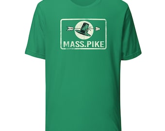 May include: Green t-shirt featuring a rectangular graphic with a hat and arrow design. The text "MASS. PIKE" is printed below the graphic in a white, distressed font. The shirt is a solid green color.