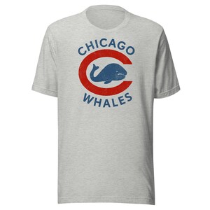以下が含まれることがあります： 「CHICAGO WHALES」の文字が青色で、赤い「C」の中に青いクジラのグラフィックが入った、ライトグレーのTシャツ。半袖でクルーネックです。